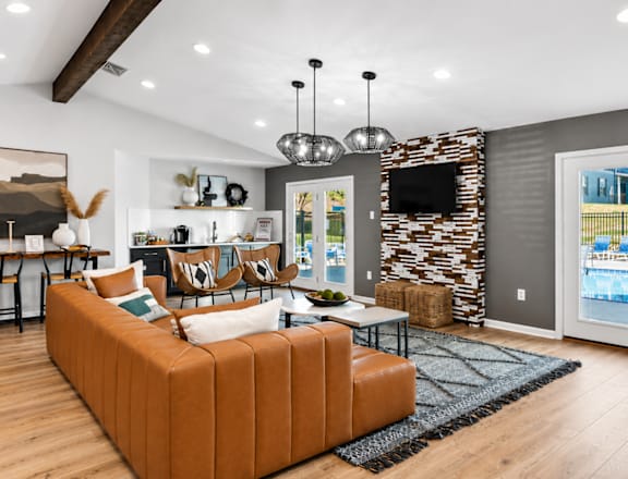 A living room with a brown sofa and a stone wall.