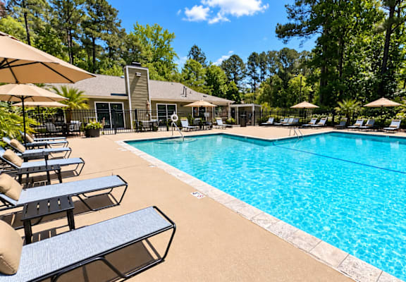 A large swimming pool surrounded by lounge chairs and umbrellas.