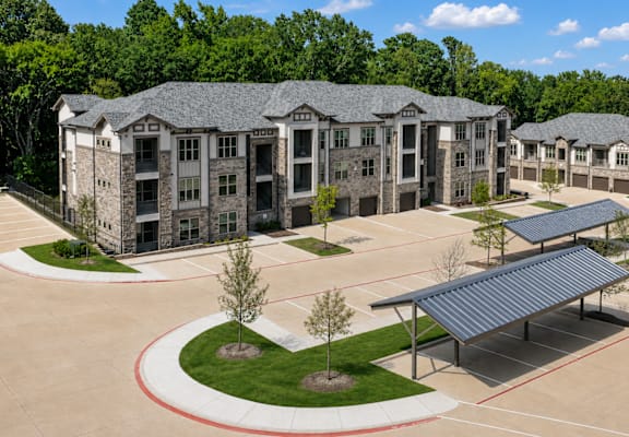 Apartment buildings and covered resident parking at Auberge of Tyler.