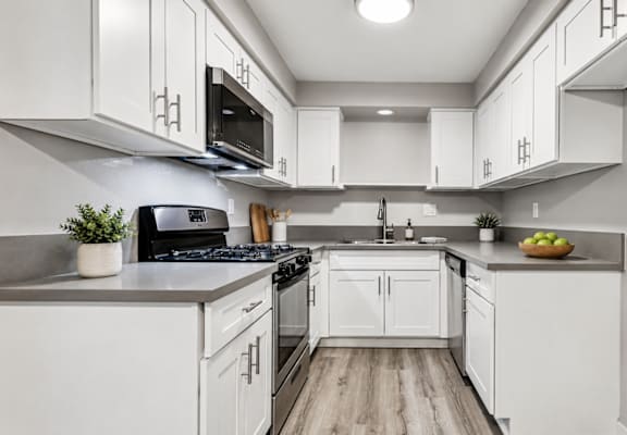 A modern kitchen with white cabinets and a wooden floor.