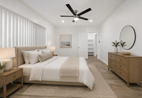 A bedroom with a large bed, a ceiling fan, and a wooden dresser.