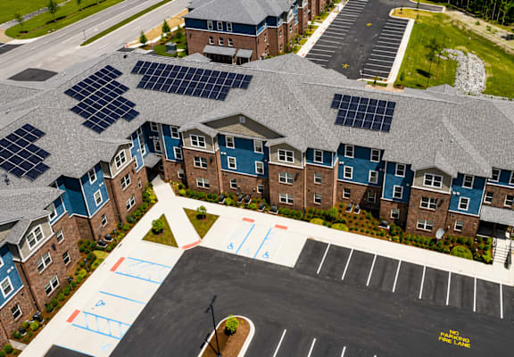 A parking lot in front of a building with solar panels on the roof.