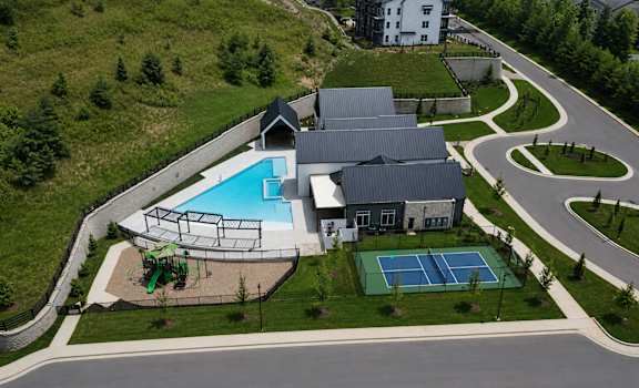 A large building with a pool and tennis court in front.