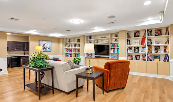 A living room with a fireplace, a couch, a chair, and a bookshelf filled with books.