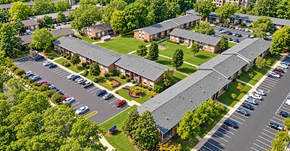 A bird's eye view of a parking lot with cars and a building with a red roof.