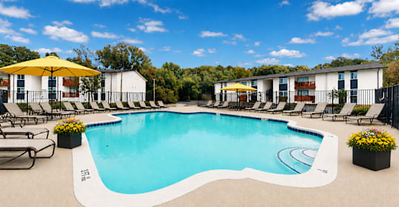 A large outdoor swimming pool surrounded by lounge chairs and umbrellas.