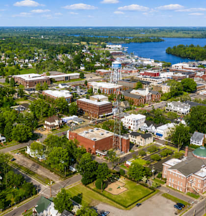 A small town with a church, a water tower, and a lake in the distance.