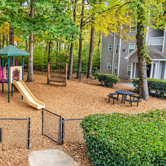 A playground with a slide, swings, and a playhouse.