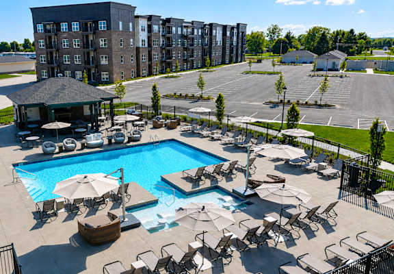 A large outdoor swimming pool surrounded by sun loungers and umbrellas.