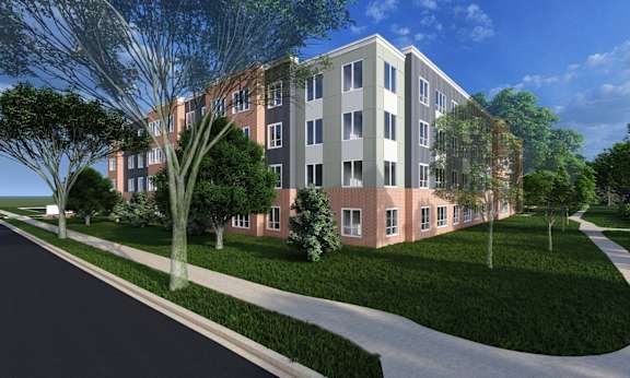 A modern building with a red brick facade and a green lawn in front.