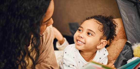 A woman and a child are reading a book together.