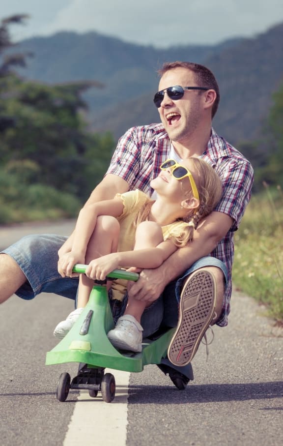 Father Smiling while Riding Small Bike with Daughter