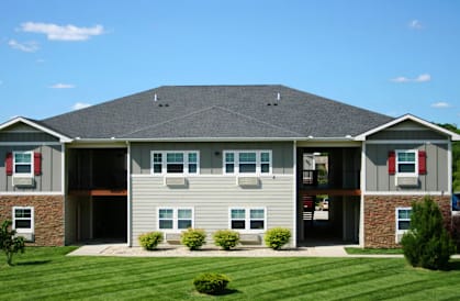 A large house with a grey roof and a green lawn in front.