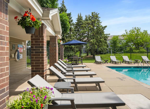 A poolside area with sun loungers and a blue umbrella.