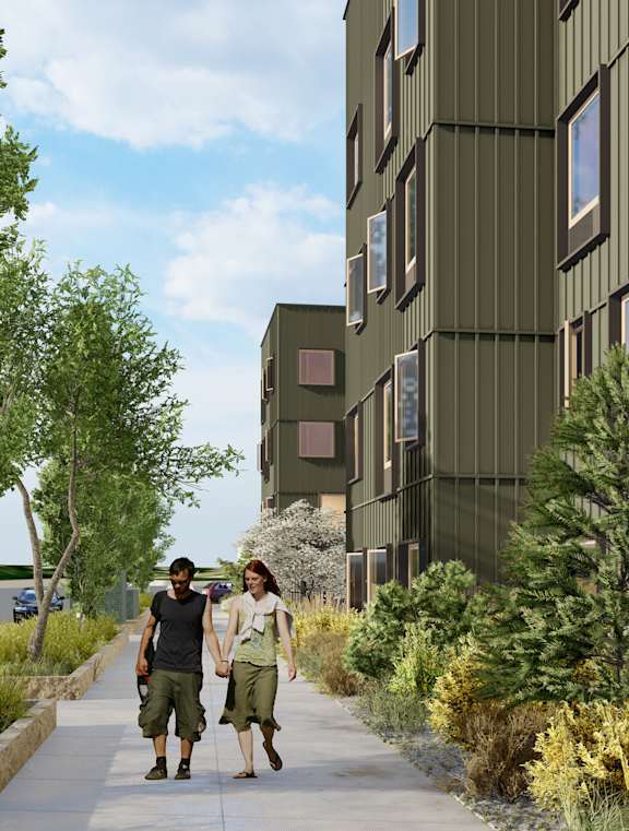 Two people walking down a sidewalk past a green building.