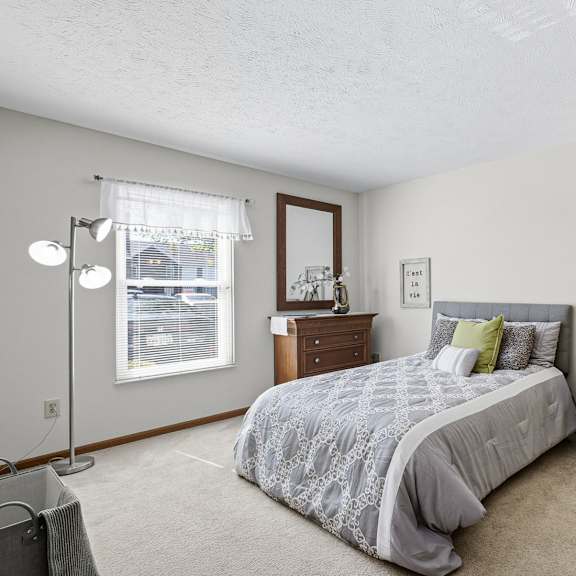 A bedroom with a bed, nightstand, and window.