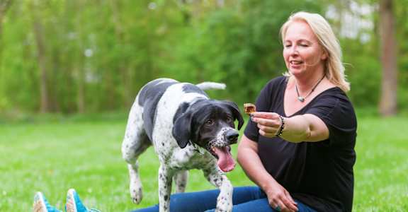 a woman sitting on the grass with her dog