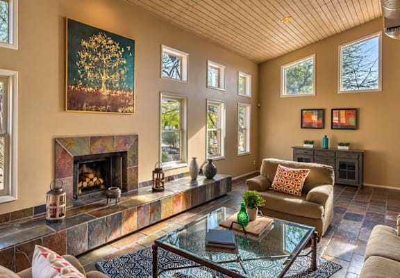 A living room with a fireplace and a painting of a tree above it.