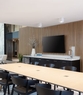a conference room with a table and chairs and a tv on the wall