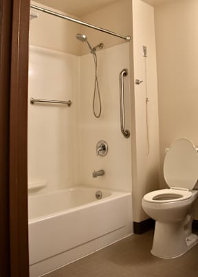 A white toilet sits next to a white bathtub in a bathroom.