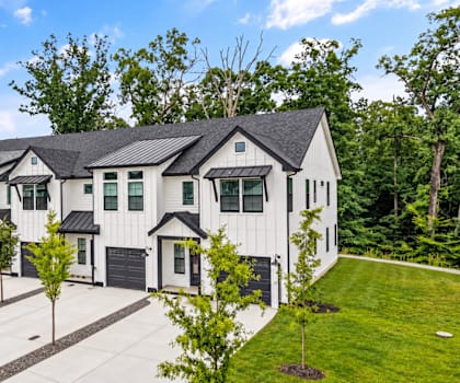 A large white house with a black roof and a driveway in front.