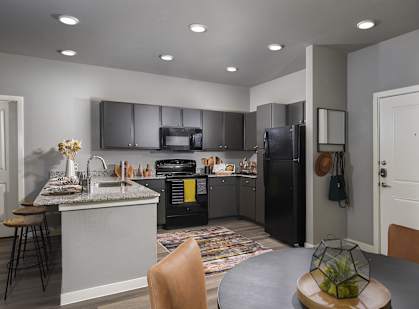 A modern kitchen with a black refrigerator and a dining table with chairs.