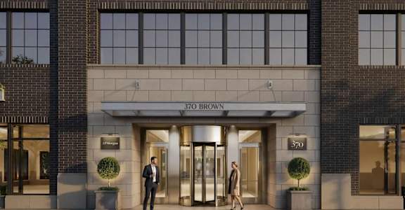 Two people stand outside a building with the number 370 on it.