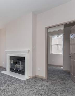 A large, empty room with a fireplace and sliding glass doors.