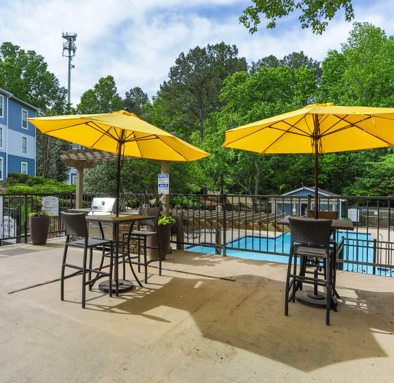 our apartments have a pool and patio with tables and umbrellas at SoCO Apartments at Vinings, Georgia, 30080