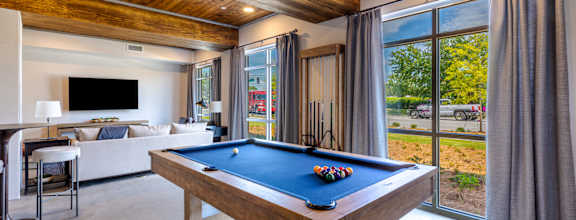A pool table in a room with a wooden ceiling and a television.