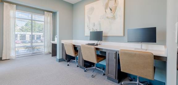 A room with a desk and chairs with a painting on the wall.