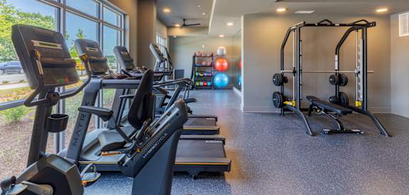 A gym with treadmills, elliptical machines, and a weight training area.