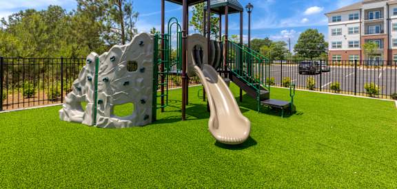 A playground with a slide, climbing wall, and a playhouse.
