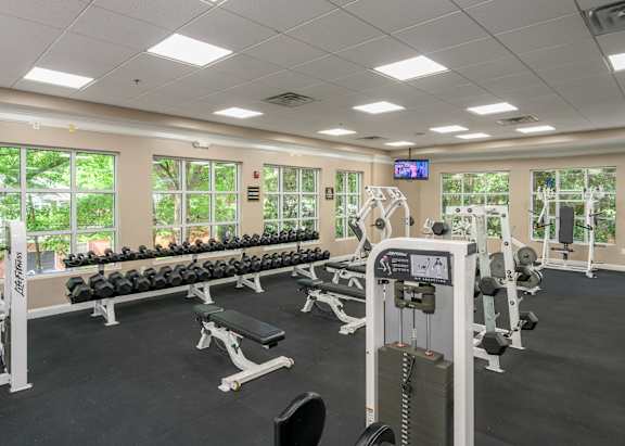 A gym with a variety of equipment including dumbbells, weight machines, and benches.