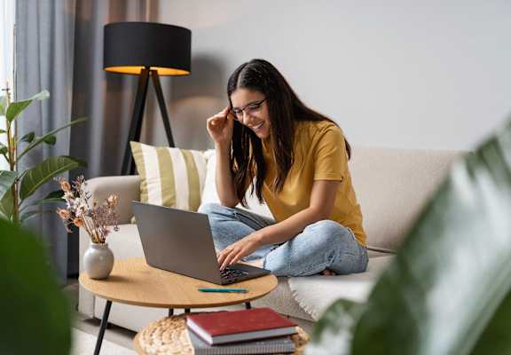 a woman sitting on a couch using a laptop computer