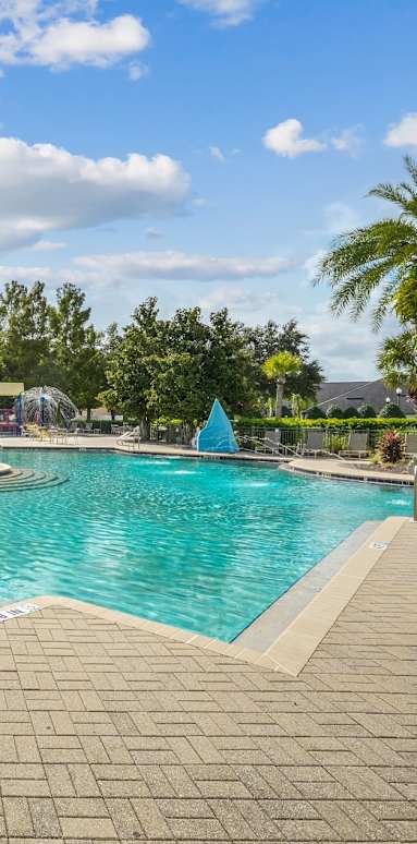 A large outdoor swimming pool surrounded by a brick patio and a covered pavilion at Wynnfield Lakes Apartments in Jacksonville, FL