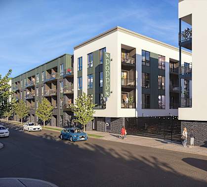 A street view of a modern apartment building with cars parked on the side of the road.