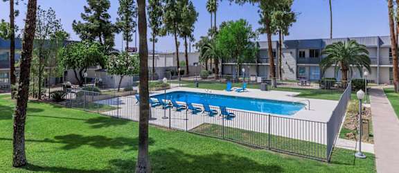 A pool surrounded by trees and a fence.