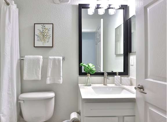 A white bathroom with a toilet, sink, mirror, and towel.