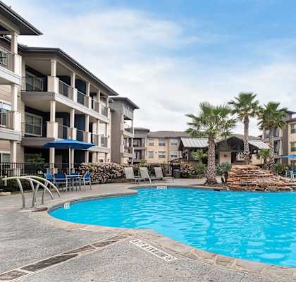 a large swimming pool with lounge chairs at Legacy Flats, San Antonio Texas