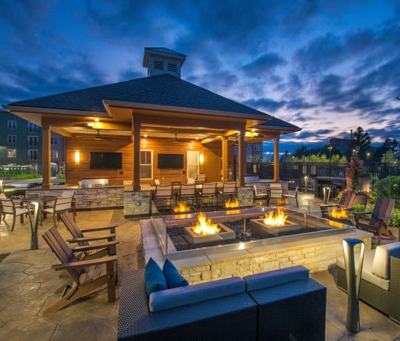 a patio with a fire pit and a gazebo at night