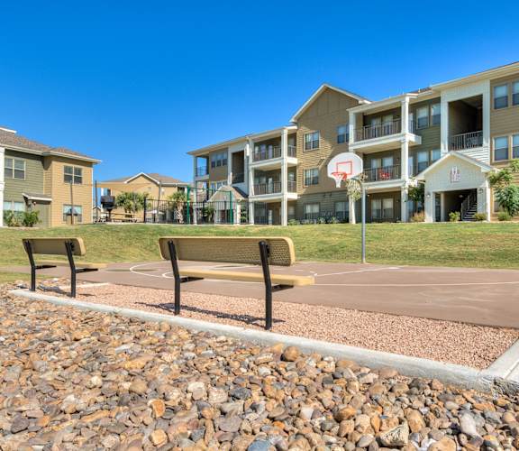 an empty park bench in front of an apartment building