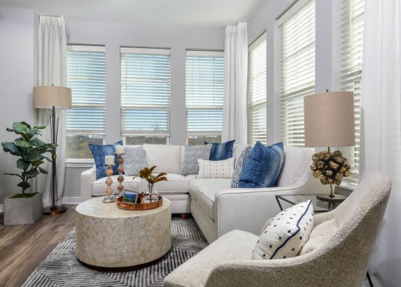 a living room with white furniture and a large group of windows