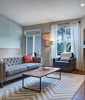 A grey couch with a red pillow sits in a living room.