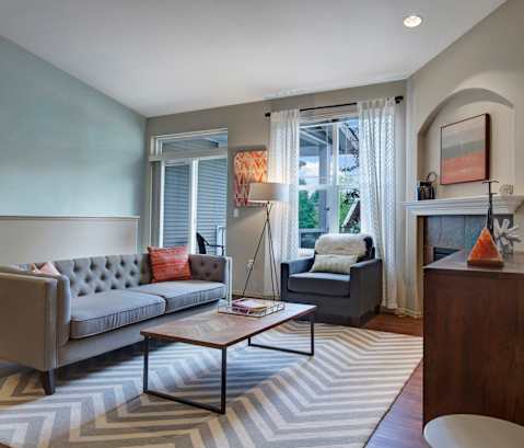 A grey couch with a red pillow sits in a living room.