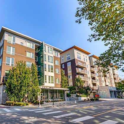 A modern apartment building with a parking lot in front.