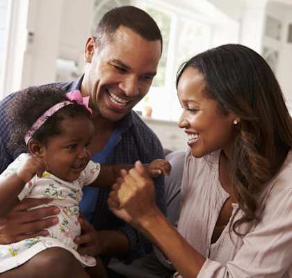 a man and woman sitting on a couch with a baby