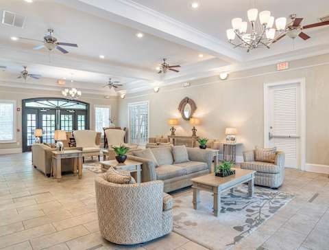 A spacious living room with a variety of seating options and a chandelier at Broadstreet at EastChase Apartments, Montgomery
