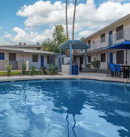 A pool in front of a building with a blue umbrella.