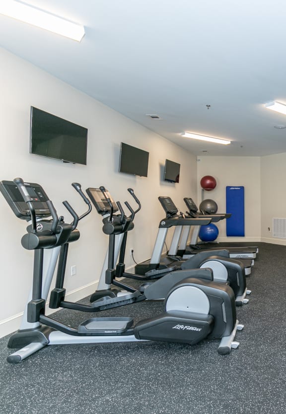 a spacious exercise room with cardio equipment and a flat screen tv at The Station at River Crossing, Macon, 31210